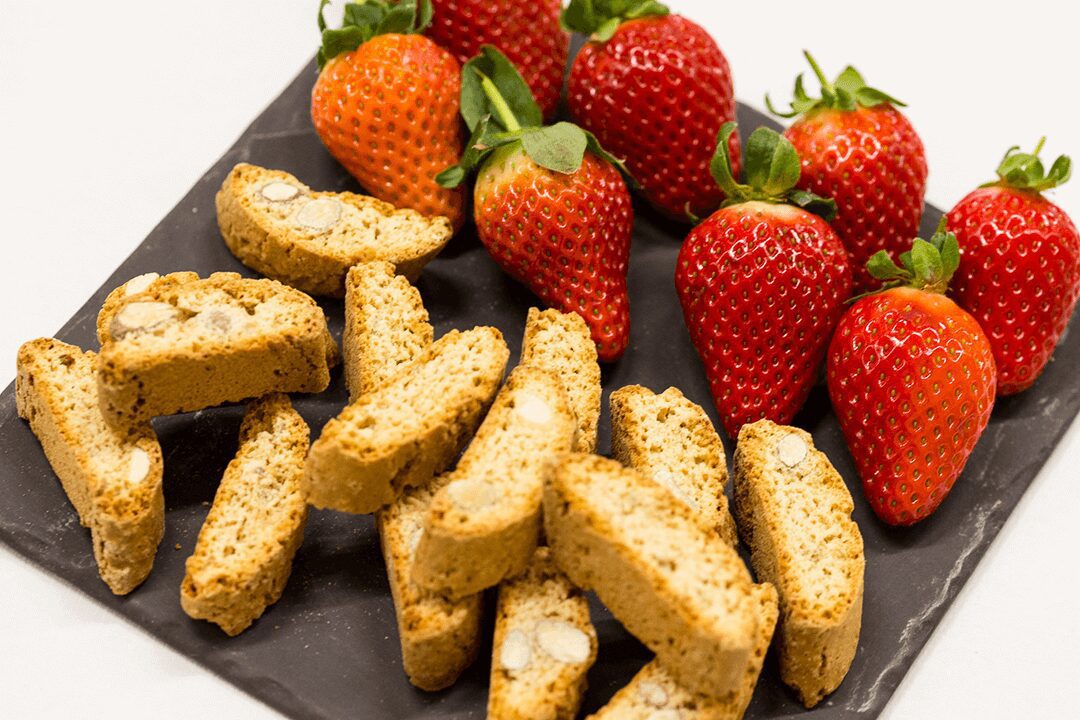 A close up of strawberries and some sliced biscotti arranged on a slate. An example of food photography by Andrew Boschier