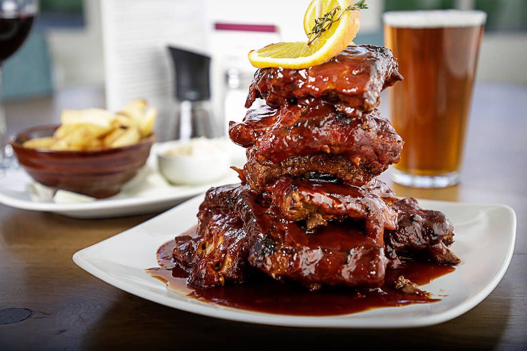 A stack of delicious looking sticky ribs on a plate of food in a pub