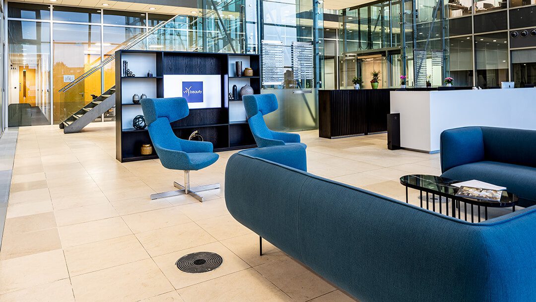 The atrium of an office development showing the reception desk and comfortable blue seating.