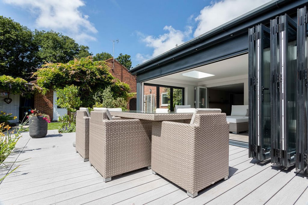 A view across the decking towards a garden room featuring the matching outdoor furniture.