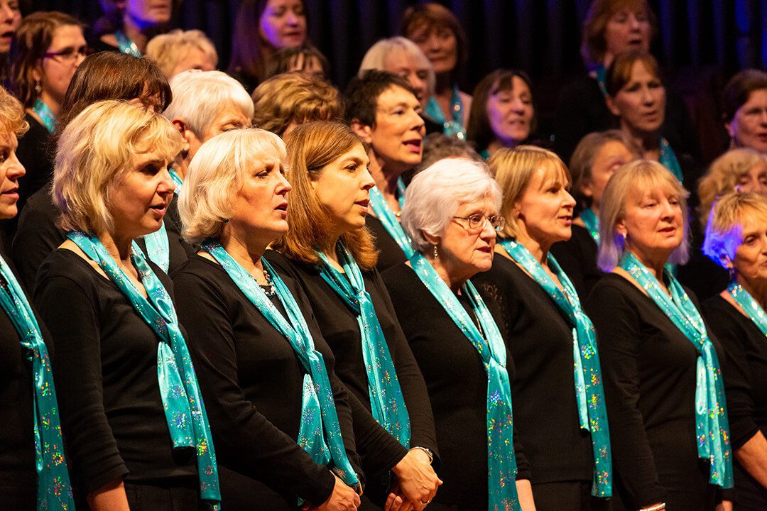 A close up of a row of the Elmbridge Ladies Choir singing at their Christmas concert in Woking