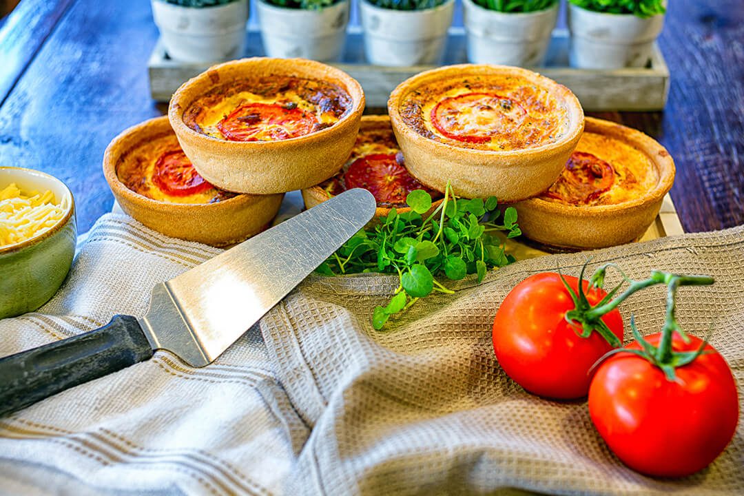 Bright coloured image of home produced tomato quiche and ingredients