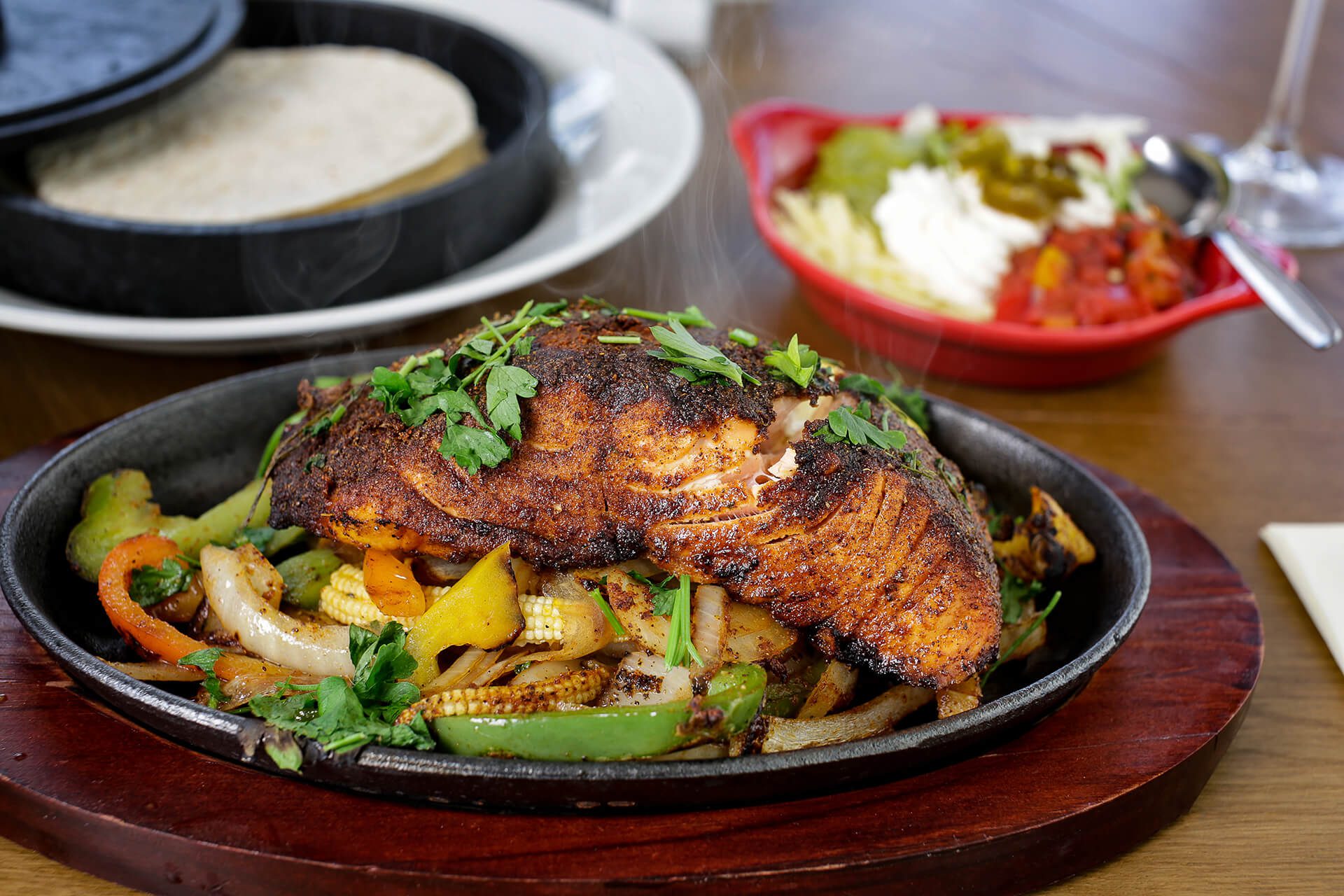 Food photography of a sizzling salmon dish presented on a bed of mixed roasted vegetables