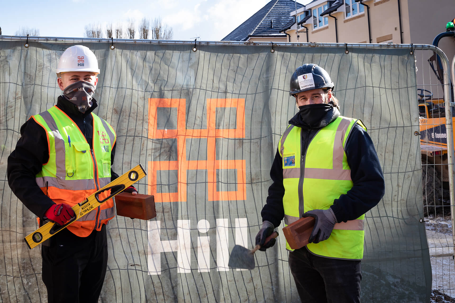 PR photography of 2 builders celebrating a collaboration for building apprentiships at a college