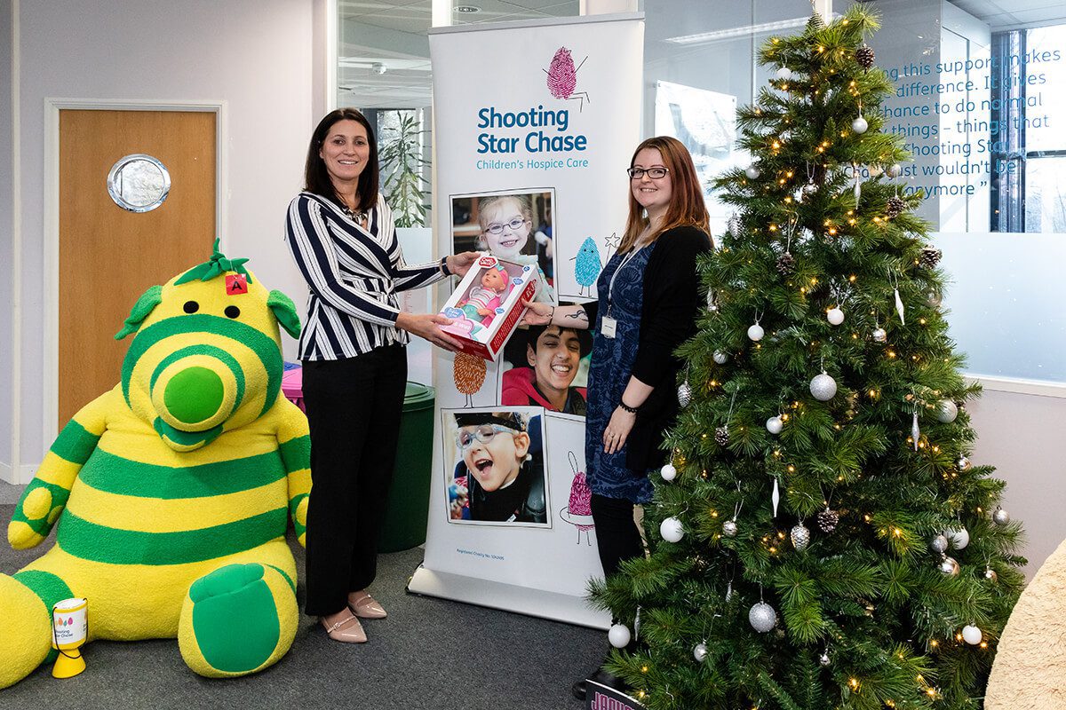 A representative from Linden Homes handing over Christmas presents to the charity Shooting Star Chase