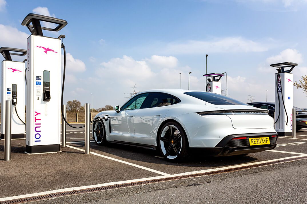 PR image of a Porsche Taycan electric vehicle being charged at a super-fast charging unit