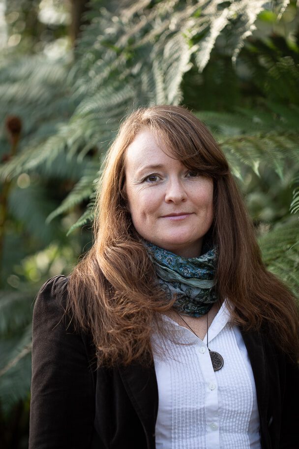 A corporate branding portrait of garden designer Tracey Parker with green ferns as a background